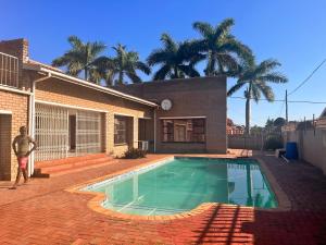 un uomo in piedi di fronte a una casa con piscina di Flamingo B&B a Richards Bay