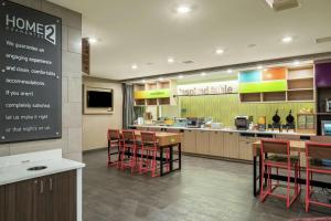 a restaurant with red chairs and a kitchen with a counter at Home2 Suites By Hilton Dayton Centerville in Centerville