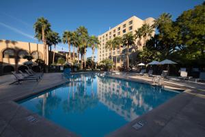 une grande piscine bordée de palmiers et un bâtiment dans l'établissement DoubleTree by Hilton Tucson-Reid Park, à Tucson