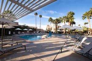 - une piscine avec des chaises blanches, des parasols et des palmiers dans l'établissement DoubleTree by Hilton Tucson-Reid Park, à Tucson