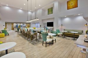 Hampton Inn & Suites Alliance في Alliance: وجود كافتيريا بالطاولات والكراسي وغرفة طعام