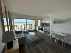a living room with a couch and a table and a kitchen at Vue mer exceptionnelle à Cabourg in Cabourg