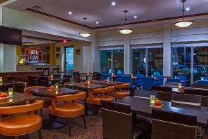 a restaurant with wooden tables and chairs and blue chairs at Hilton Garden Inn Cleveland Airport in Fairview Park