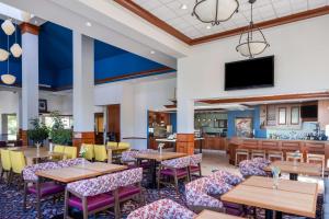 una sala da pranzo con tavoli, sedie e TV a schermo piatto di Hilton Garden Inn Mystic/Groton a Groton