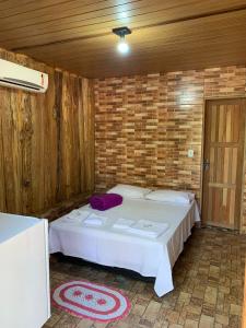 a bedroom with a white bed in a brick wall at pousada camping do josias in Nobres