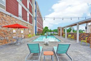 a swimming pool with chairs and a table and an umbrella at Home2 Suites By Hilton Meridian in Meridian