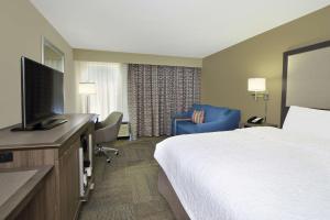 a hotel room with a bed and a flat screen tv at Hampton Inn Madison in Madison