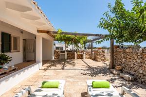 un patio con sillones y una pared de piedra. en Casita Estancia d'en Carretero- Biniarroca en Es Castell