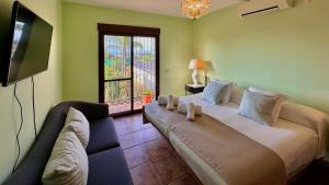 een slaapkamer met een bed, een bank en een televisie bij Villa Huerta del Sur - Piscina privada y barbacoa in Alhaurín el Grande