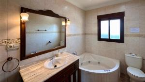 een badkamer met een wastafel, een bad en een toilet bij Villa Huerta del Sur - Piscina privada y barbacoa in Alhaurín el Grande