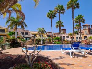 a pool with two chairs and palm trees next to it at Modern Townhouse Ocean Front in Adeje