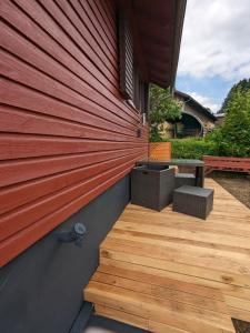 a wooden deck next to a building with a red wall at Ferienhaus Tinyhouse21 Wasserkuppe in Obernhausen