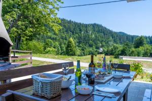 Una mesa de madera con copas de vino y comida encima. en Mountain Escape house with indoor pool, en Fužine