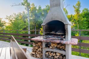 a wood fired oven with a pile of wood at Mountain Escape house with indoor pool in Fužine