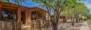 a house with a wooden fence and trees at Lodge Altitud in San Pedro de Atacama