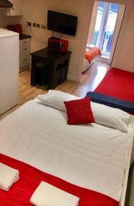 a bedroom with a white bed with red and white pillows at One Bedroom Flat in Central London in London