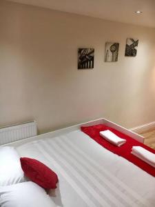 a bedroom with a white bed with red pillows at One Bedroom Flat in Central London in London