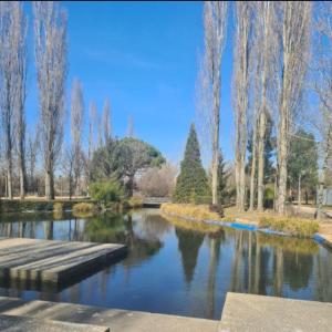 a pond in a park with trees and a bridge at EL RINCÓN DE CHAVELY in Palencia