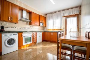 cocina con armarios de madera, mesa y lavavajillas en Casa Palau, en Morella