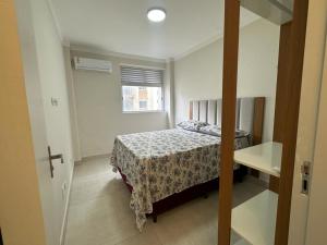 a small bedroom with a bed and a window at Refúgio Costeiro in Guarujá