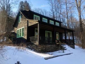 una pequeña casa en la nieve en el bosque en Mountain Farmhouse (The Lorca, Catskills), en Shandaken