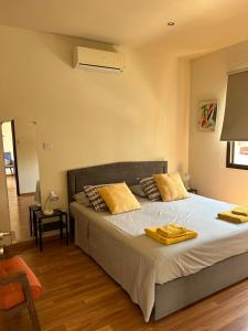 1 dormitorio con 1 cama grande con almohadas amarillas en Extremely comfy 10min walk to Beach & Town en Lárnaca