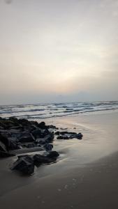 a beach with rocks in the sand and the ocean at 5 Mile Beach Resort in Kumta