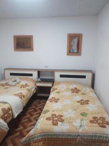 a bedroom with two beds and two pictures on the wall at Hostal Casa Grande in Villazón
