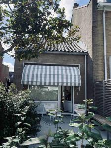 een patio met 2 stoelen en een luifel op een huis bij Tiny beachhouse - free parking in Noordwijk