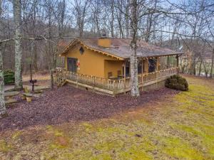 una pequeña casa amarilla con un porche en el bosque en Luxury Cabin w/ Jacuzzi-Fireplace & Amazing View - Heidi, en Blairsville