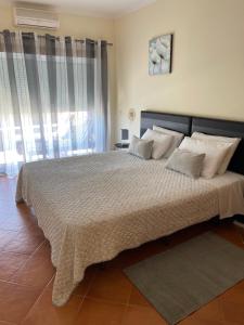 1 dormitorio con 1 cama grande con almohadas blancas en Condominio do Mar, en Lagos