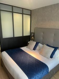 a bedroom with a large bed with blue and white pillows at Hotel Best Western La Mare Ô Poissons in Ouistreham