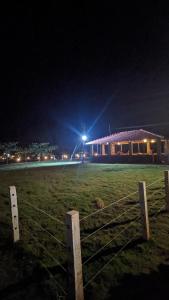 un campo con una valla delante de un edificio por la noche en 5 Mile Beach Resort, en Kumta