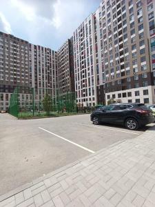 a car parked in a parking lot in front of tall buildings at Altyn Dala in Taldykolʼ
