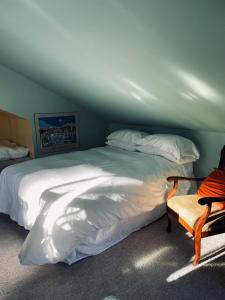 ein Schlafzimmer mit einem großen weißen Bett und einem Stuhl in der Unterkunft Lantzville Treehouse in Lantzville
