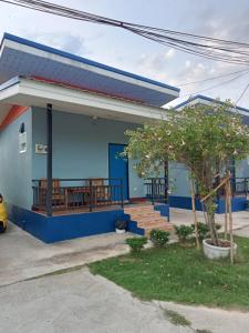 a blue house with a porch and a tree at หม่อนเมือง รีสอร์ท in Chiang Rai