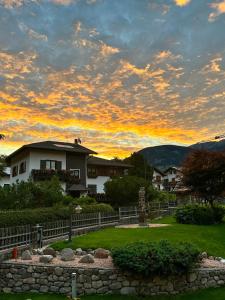 ein Haus mit einem Zaun in einem Hof mit Sonnenuntergang in der Unterkunft La locanda di Geppetto in Bedollo