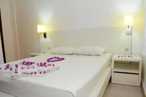ein Schlafzimmer mit einem weißen Bett, das mit lila Blumen verziert ist in der Unterkunft Bodrum Park Hotel in Gümbet + 83 Fotos