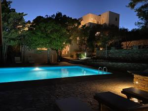 a swimming pool at night with a house in the background at Apaggio Apartments in Katapola