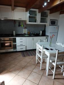 a kitchen with white cabinets and a table and chairs at Casa Franco in Ponta do Pargo