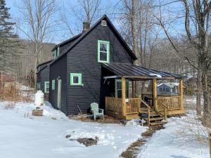 a black house with a deck in the snow at Modern Cottage Two (The Lorca, Catskills) in Shandaken