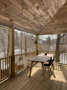 a wooden porch with a table and chairs on a deck at Modern Cottage Two (The Lorca, Catskills) in Shandaken