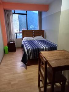 1 dormitorio con cama, mesa y ventana en Hostal Garcilaso - Garaje Amplio, en Abancay