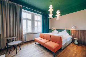 a bedroom with a bed and a chair and a window at Hotel Amalia - Boutique Hotel in Landshut