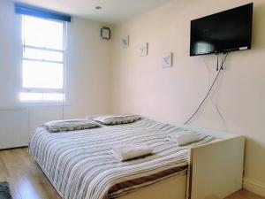 a bedroom with a bed with a flat screen tv on the wall at Cosy Studio Flat in Great Locationin London in London