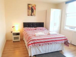 een slaapkamer met een groot bed met een rode en witte deken bij Cosy Studio Flat in Great Locationin London in Londen
