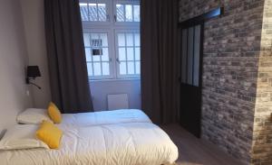 a bedroom with a bed and a brick wall at Le Relais du Chapeau Rouge in Saint Loup Lamaire