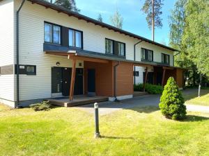 Cette grande maison blanche dispose d'une terrasse couverte et d'une cour. dans l'établissement Kylpyla SPA, lake saimaa villa, à Imatra