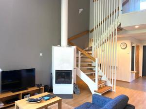 a living room with a tv and a staircase at Kylpyla SPA, lake saimaa villa in Imatra