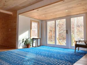um quarto amplo com um tapete azul e uma janela grande em Stream House (The Lorca, Catskills) em Shandaken